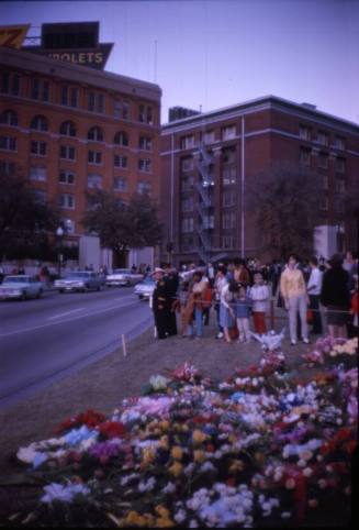 Image of crowds gathered at flower memorials in Dealey Plaza