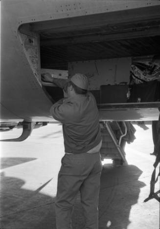 Image of an airport worker putting cases in the luggage compartment of a plane