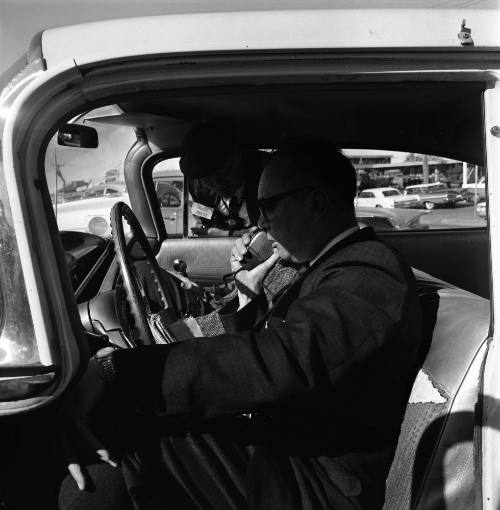 Image of two men in a car outside Parkland Hospital using a radio telephone