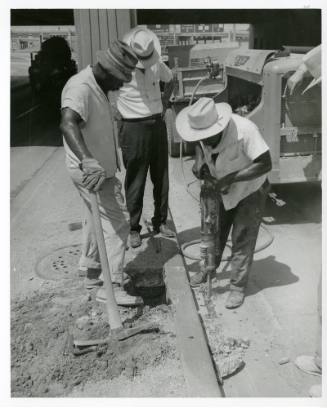 Photograph of men removing a section of curb from Main Street in Dealey Plaza