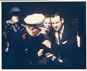 Color photograph of Oswald under arrest at the Texas Theatre