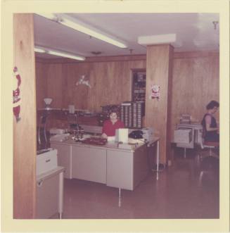 Color photograph of a woman at her desk in the Texas School Book Depository