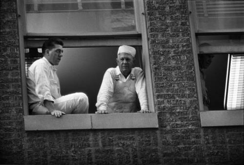 Image of workers looking out a window above Main Street awaiting the motorcade