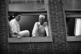 Image of workers looking out a window above Main Street awaiting the motorcade