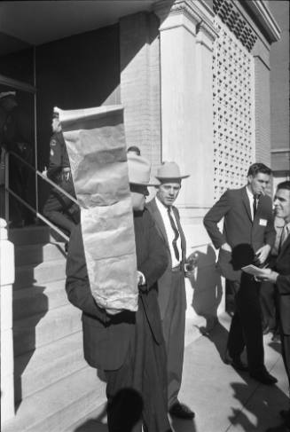 Image of Dallas Police detectives carrying evidence out of the Book Depository