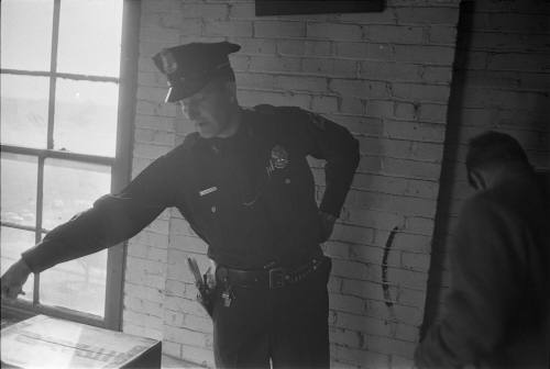 Image of a Dallas Police officer pointing to the location of the rifle