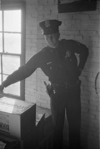 Image of a Dallas Police officer pointing to the location of the rifle