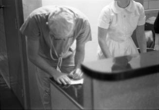 Image of a Parkland doctor completing paperwork on November 24, 1963