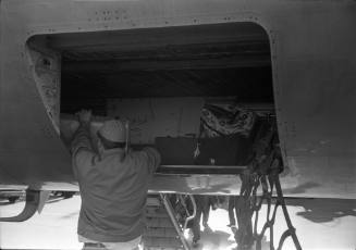 Image of an airport worker putting cases in the luggage compartment of a plane