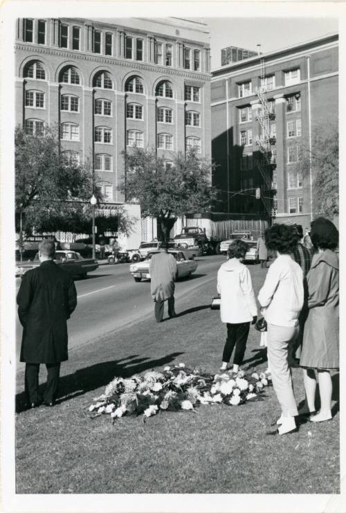 Black and white photograph of mourners and flowers in Dealey Plaza