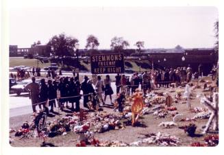 Color photograph of mourners and memorial flowers in Dealey Plaza