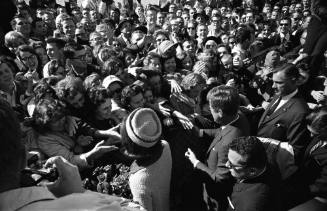 Image of the Kennedys greeting the crowd along the Love Field fence line