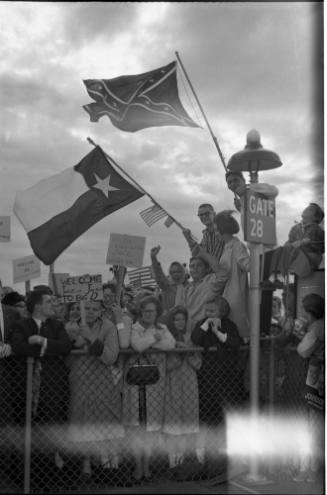 Image of the crowd holding signs and waving flags at Dallas Love Field