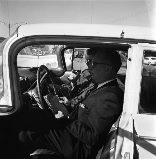 Image of two men in a car outside Parkland Hospital using a radio telephone