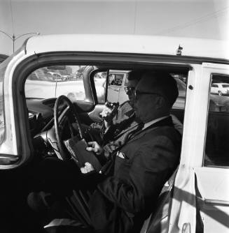 Image of two men in a car outside Parkland Hospital using a radio telephone