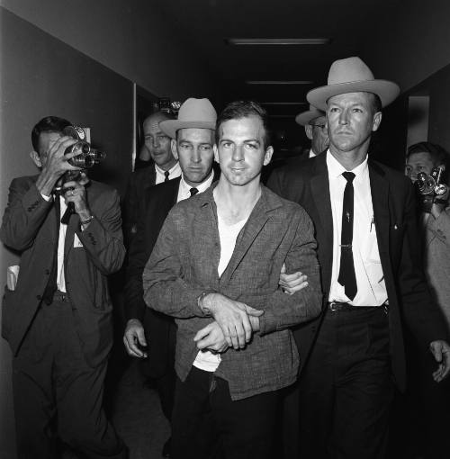 Image of Lee Harvey Oswald in handcuffs at the Dallas Police Department