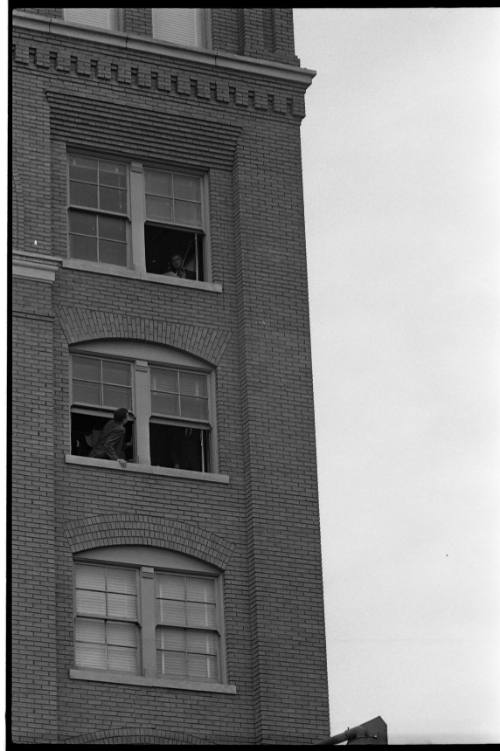 Image of men in the fifth and sixth floor corner windows of the Book Depository