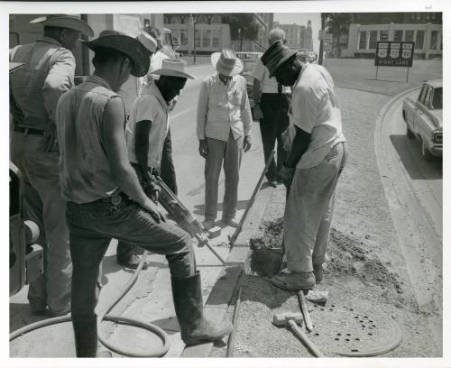 Photograph of men removing a section of curb from Main Street in Dealey Plaza