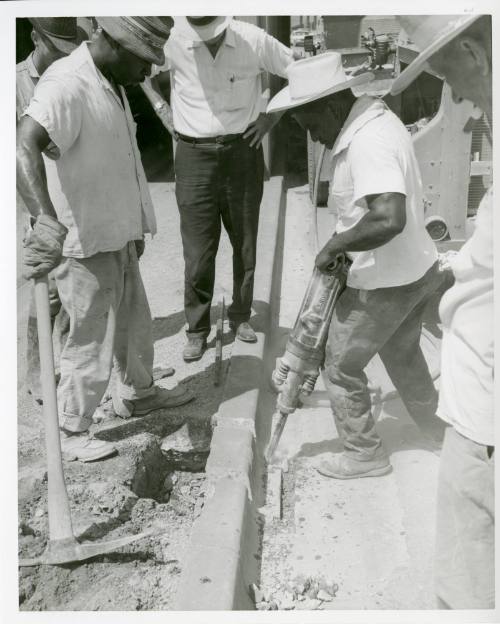 Photograph of men removing a section of curb from Main Street in Dealey Plaza