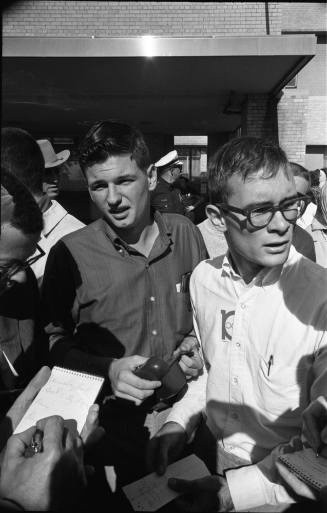 Image of two young men talking to reporters outside Parkland Hospital