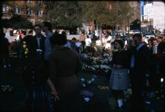 Image of mourners and memorial flowers in Dealey Plaza after the assassination