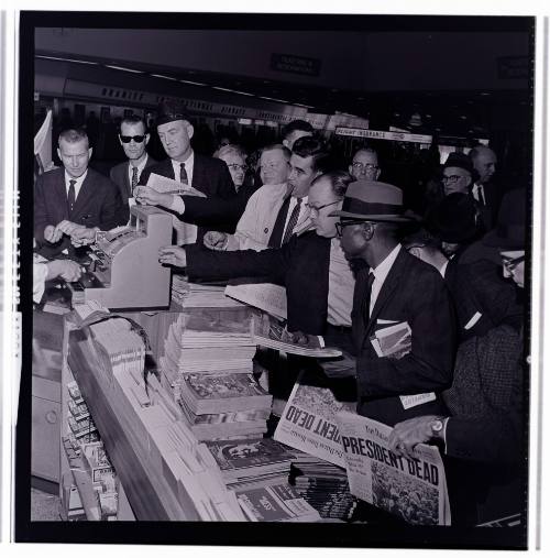 Image of crowd gathered around a newsstand at Love Field on November 22, 1963