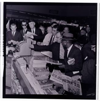 Image of crowd gathered around a newsstand at Love Field on November 22, 1963