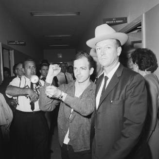 Image of Lee Harvey Oswald in handcuffs at the Dallas police headquarters