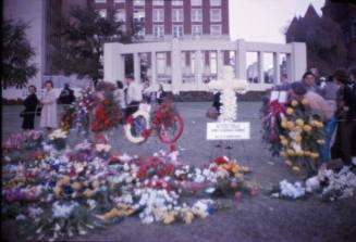 Image of flowers and crowd of mourners in Dealey Plaza