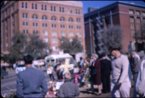 Image of the Texas School Book Depository building and mourners in Dealey Plaza